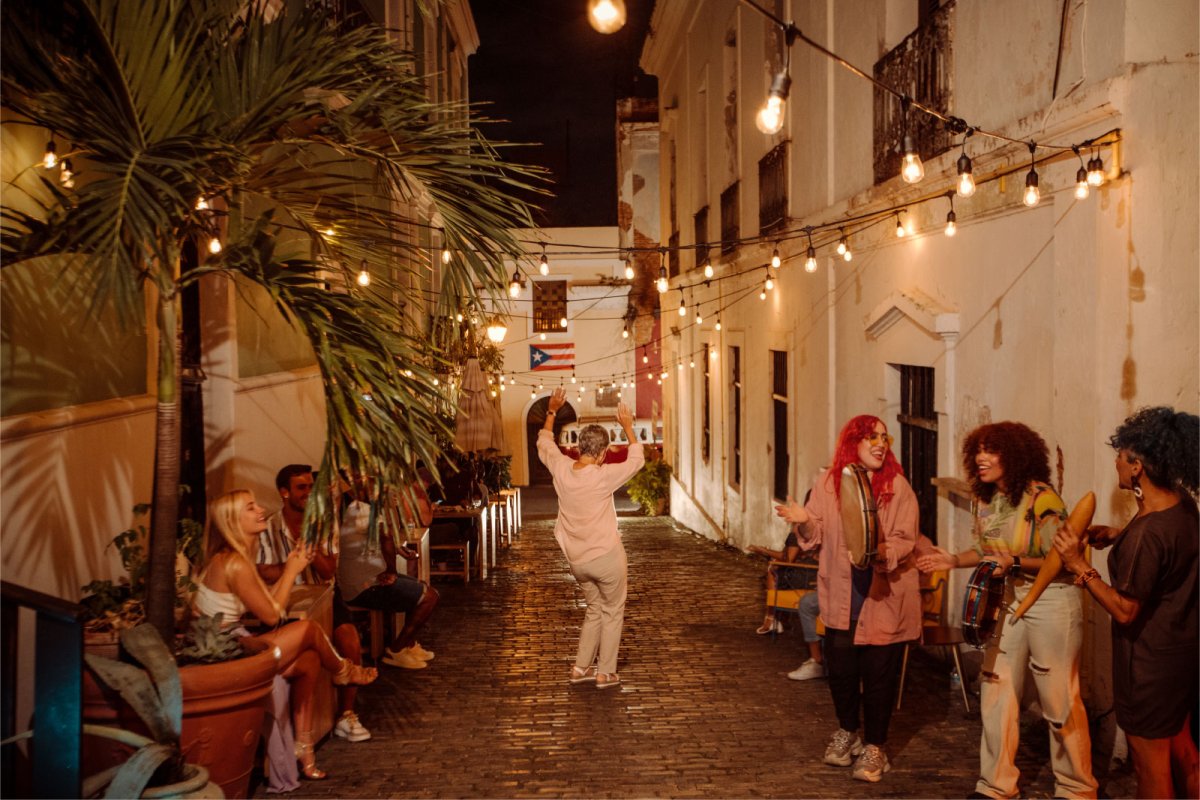 A woman dances on a cobblestone street while a band plays in Old San Juan, Puerto Rico
