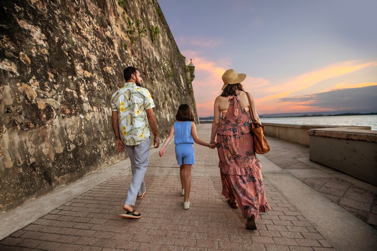 A family walks oceanside along the Paseo de la Princesa in Old San Juan.