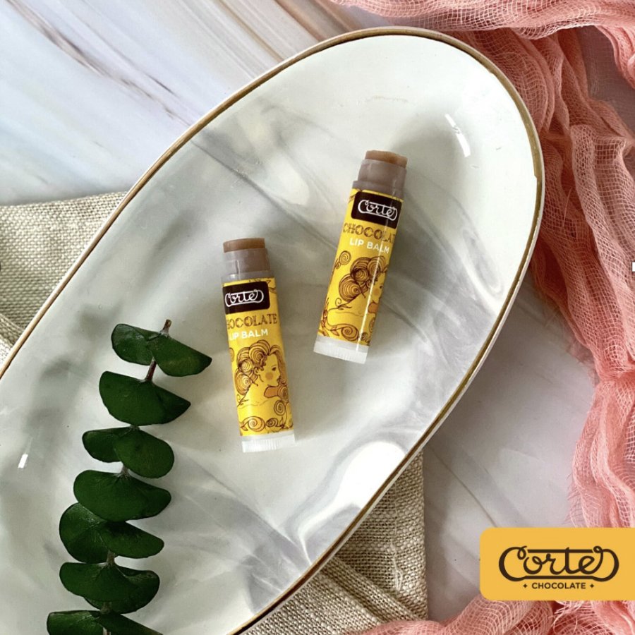 Overhead shot of two tubes of chocolate lip balm from Chocobar Cortes in a decorative dish with various decorative elements.