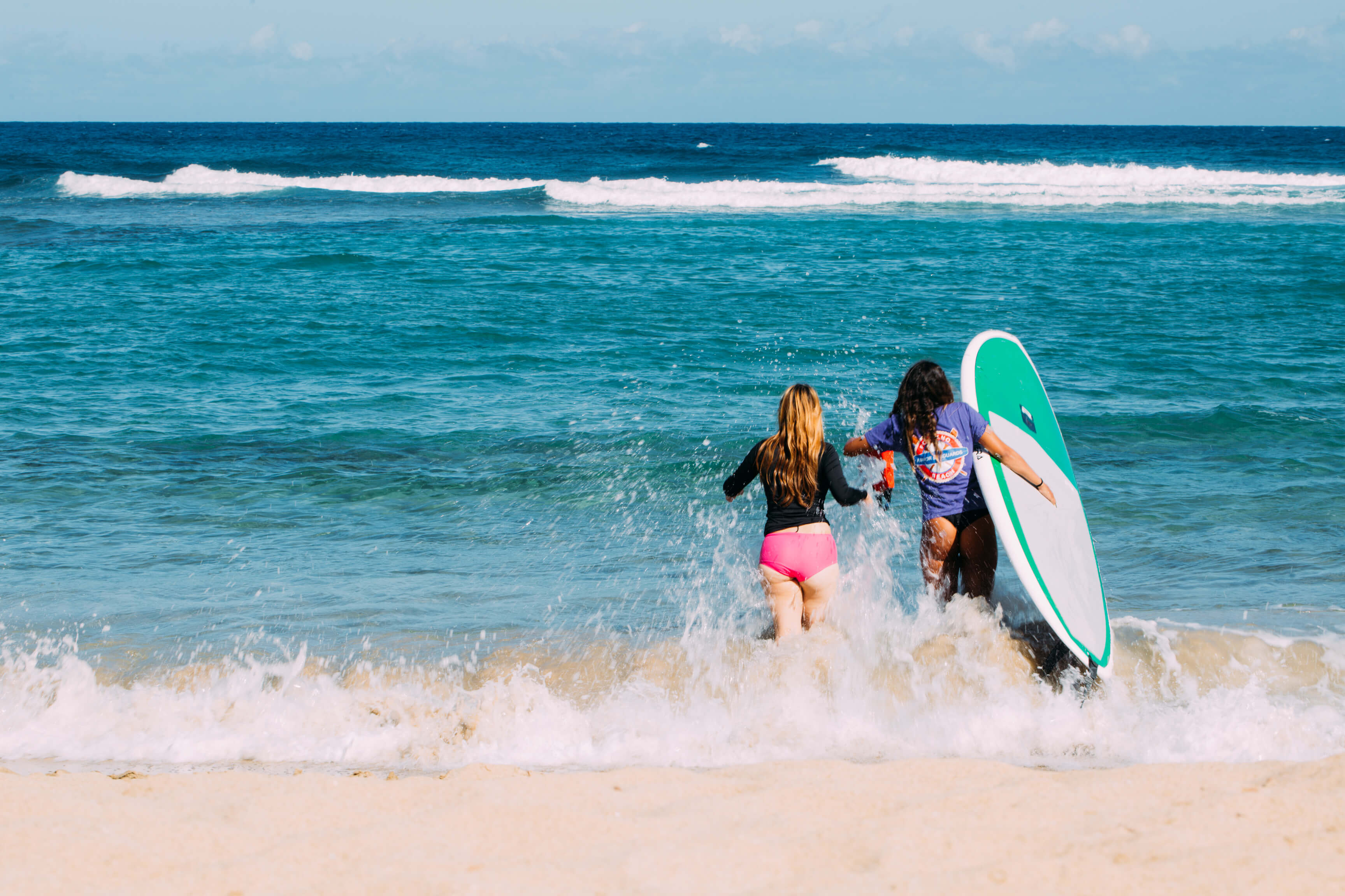 Dos mujeres corren entre las olas en Playa Jobos en Isabela.