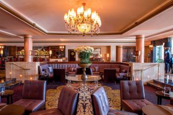 El elegante salón del hotel Condado Vanderbilt incluye tapicería de cuero, columnas de mármol y un candelabro adornado.