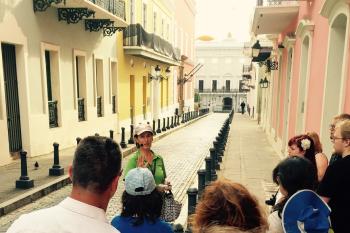 A female tour guide leads a group on a walking tour of Old San Juan.