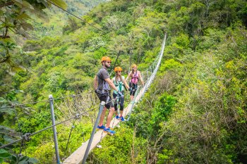 A group of people stand on a suspended bridge at Toro Verde Nature Adventure Park.