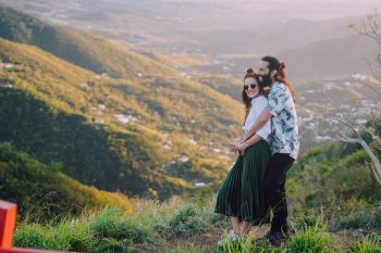 Una pareja se abraza sobre un hermoso valle de montañas.