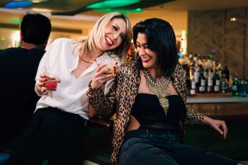 A couple of lesbians enjoying their cocktails at a bar.