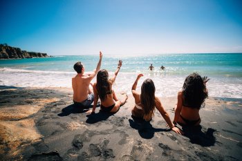 Un grupo de hombres y mujeres disfrutan de las aguas turquesas en la Playa de Arena Negra en Vieques.