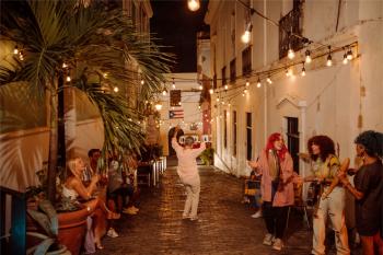 A woman dances on a cobblestone street while a band plays in Old San Juan, Puerto Rico