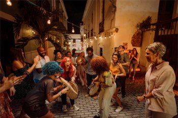 A group of people play instruments and dance in the street in Old San Juan