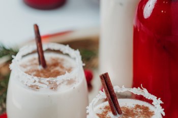 Coquito glasses are decorated with cinnamon sticks. 