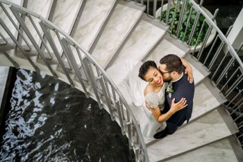 Overhead wedding photo of a couple embracing on a spiral staircase over water at La Concha Renaissance Resort. San Juan, Puerto Rico.