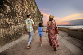 A family walks oceanside along the Paseo de la Princesa in Old San Juan.