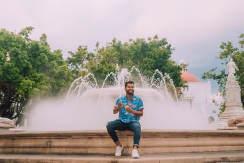 Man enjoying his ice cream while sitting on the ledge of a large fountain in downtown Ponce.