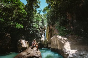 Person siting on a rock in front of a waterfall