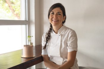 Chef Lucía at her patiserrie posing next to a cake.