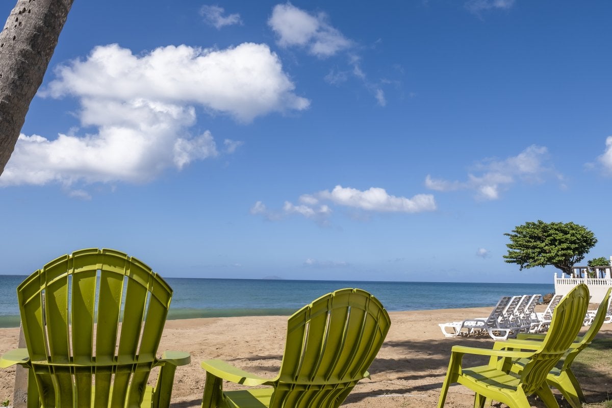 a set of chairs on the beach facing the water