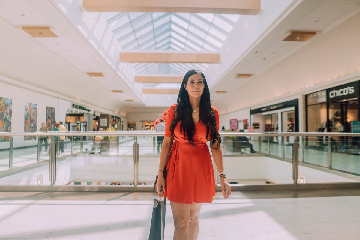 Una mujer camina por el centro comercial con una bolsa en la mano.