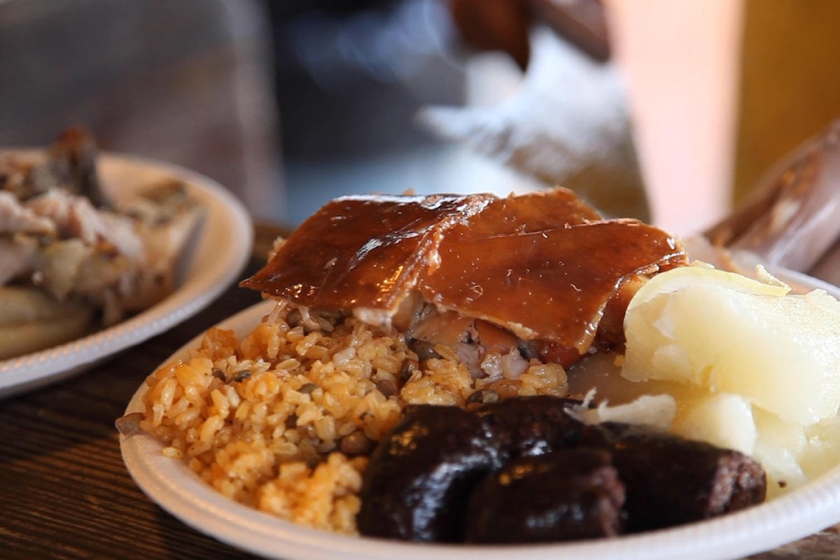 Lechón asado, arroz y gandules y morcilla en un plato.