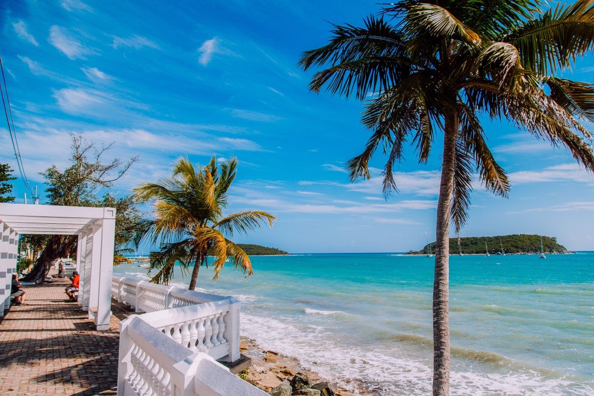 People walking along a paved sidewalk  in front of the ocean in Vieques.