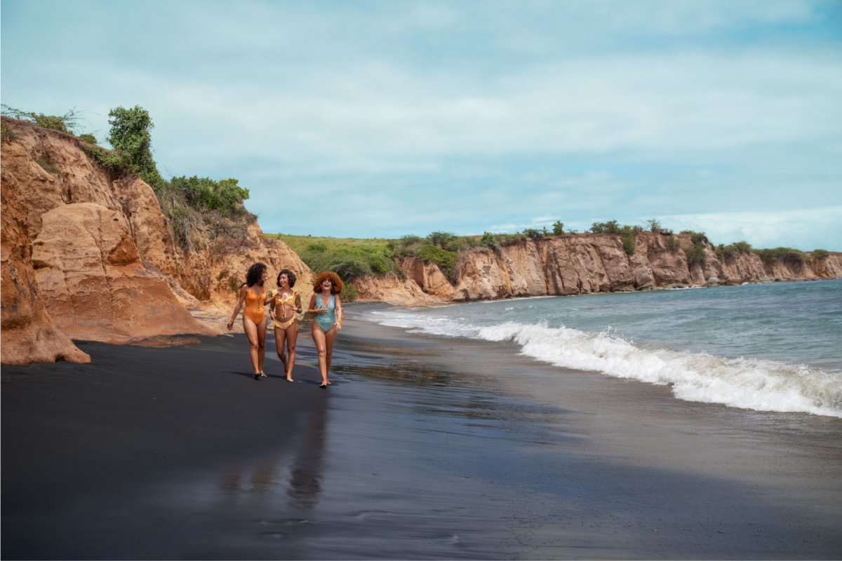 A group of women walk along Playa Negra black sand beach in Vieques, Puerto Rico