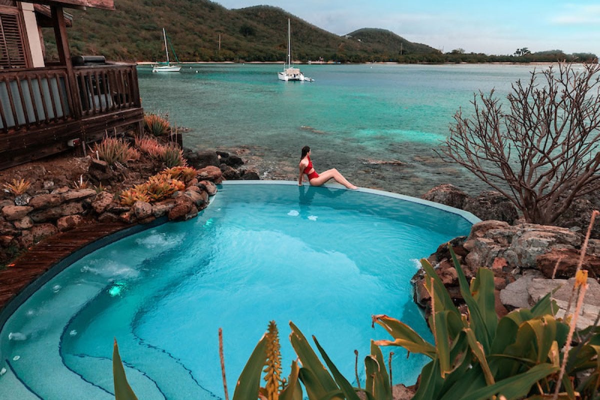 A woman perches on the edge of a private pool overlooking the ocean at a vacation rental in Puerto Rico.