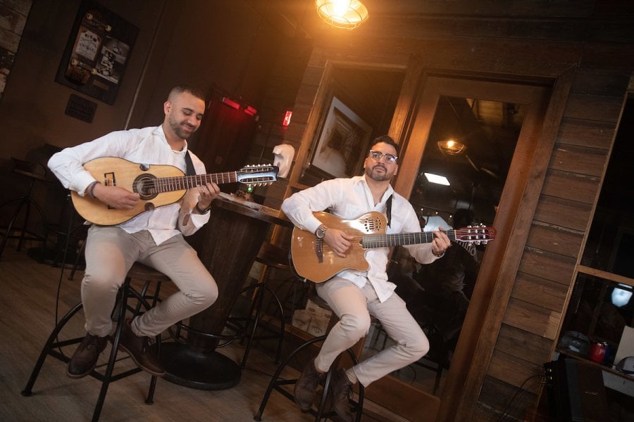 Two people playing a guitar and the cuatro, a traditional Puerto Rican instrument.