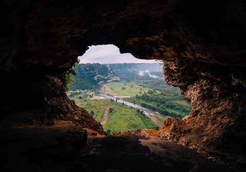 A cave opening reveals a green valley at Cueva Ventana.