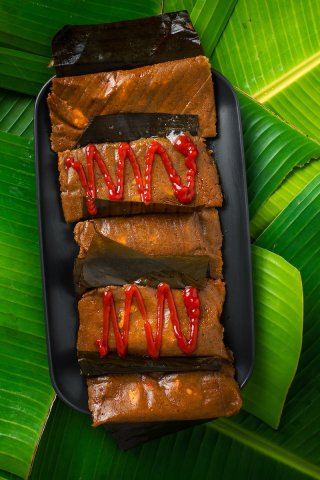 Plate of pasteles with and without ketchup on top of banana leaves.