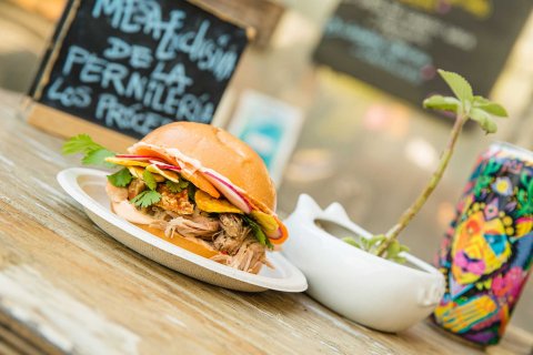 A sandwich with many toppings and a colorful can of beer are pictured on a table at Lote 23, a food truck park in the Santurce neighborhood of San Juan, Puerto Rico.