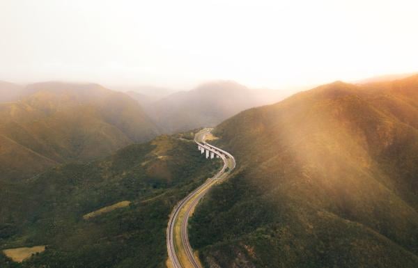 Aerial shot showing a curving stretch of highway winding through a mountain pass