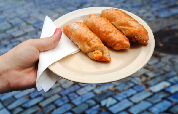 A woman's hand holding a plate with quesitos.