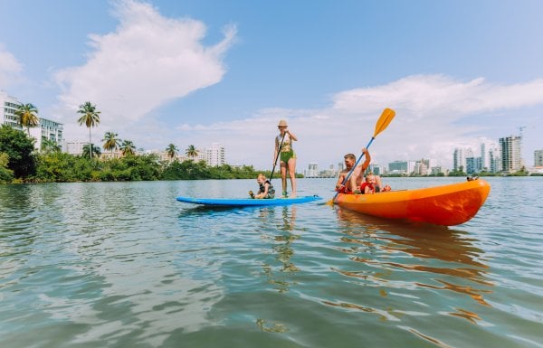 A family of four enjoying their kayak and paddle board at the Condado Lagoon.