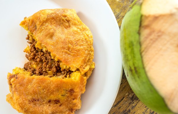 Puerto Rican fritter known as pionono served in a plate with a coconut next to it. 