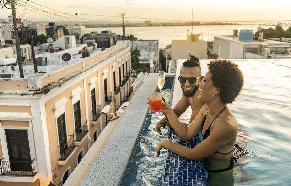 A couple enjoys cocktails in a rooftop pool in Old San Juan