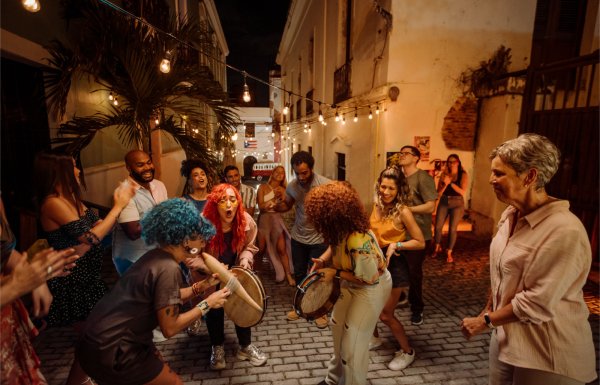 A group of people dance and play music in a street in Old San Juan, Puerto Rico