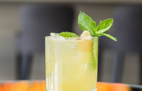 A lime-colored rum cocktail with a green garnish sits on a table.