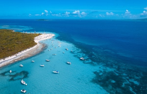 Overhead view of the coastline of Cayo Icacos on the east coast of Puerto Rico, with clear-blue water and several boats anchored near the shore.