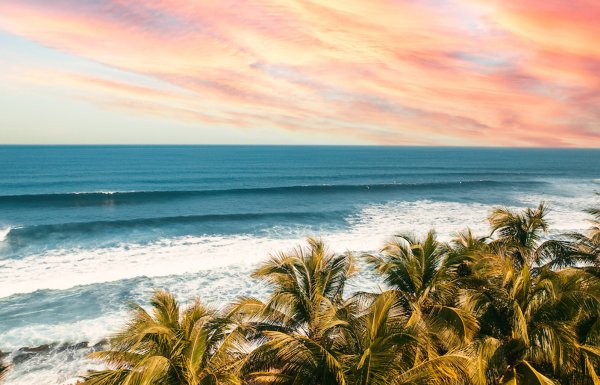 The sun setting, painting the sky a color of orange and pink, over the pristine waters of the beaches in Aguadilla, Puerto Rico.