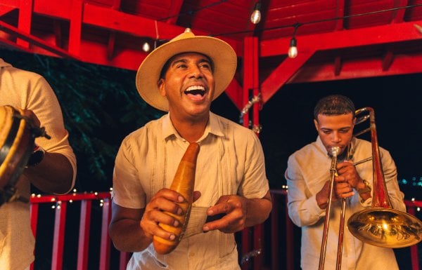 A group of musicians playing the trumpet and güiro, a traditional Puerto Rican instrument.