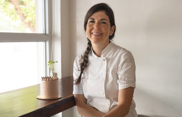 Chef Lucía at her patiserrie posing next to a cake.