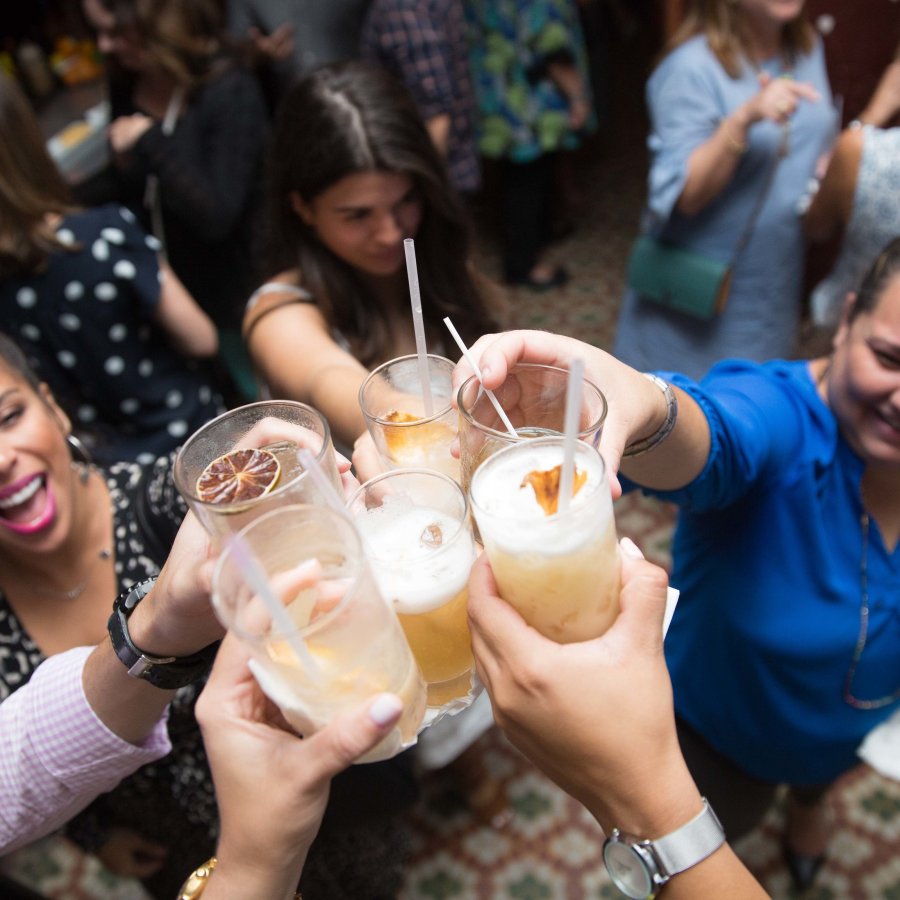 A group of friends toasts their drinks at a bar. 