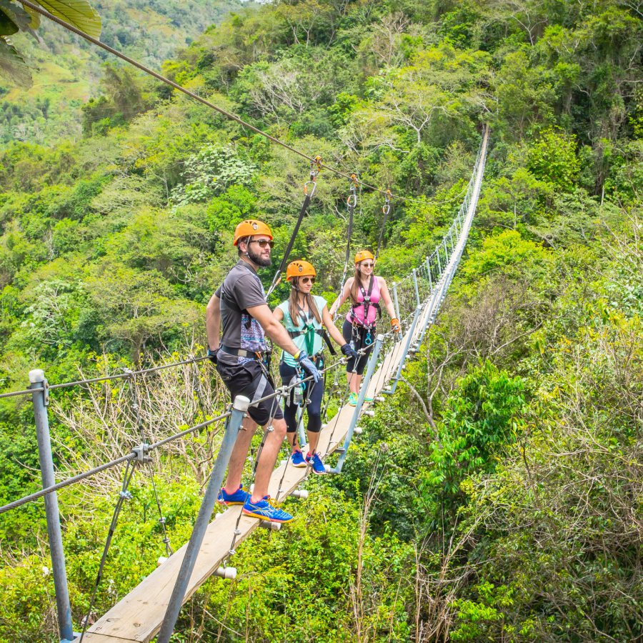 A group of people stand on a suspended bridge at Toro Verde Nature Adventure Park.