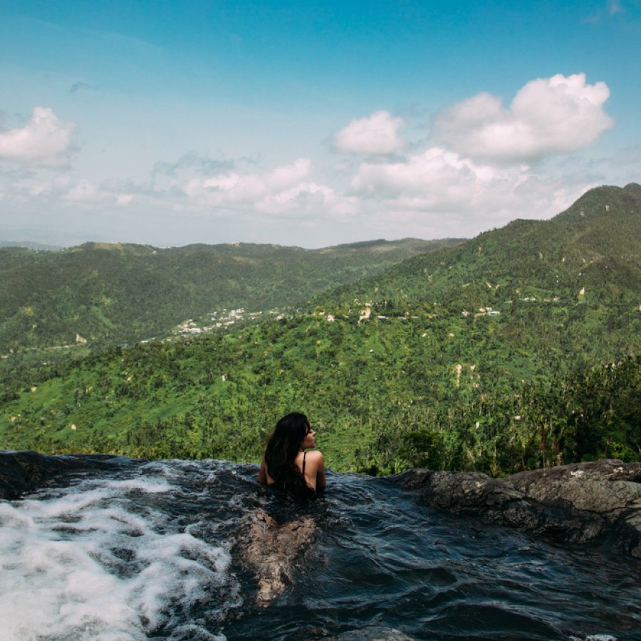 A woman looks out over an expansive view of forested mountains