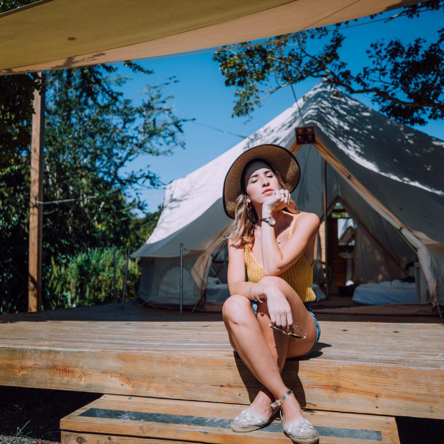 Una niña sentada frente a una tienda de campaña en Pitahaya Glamping.