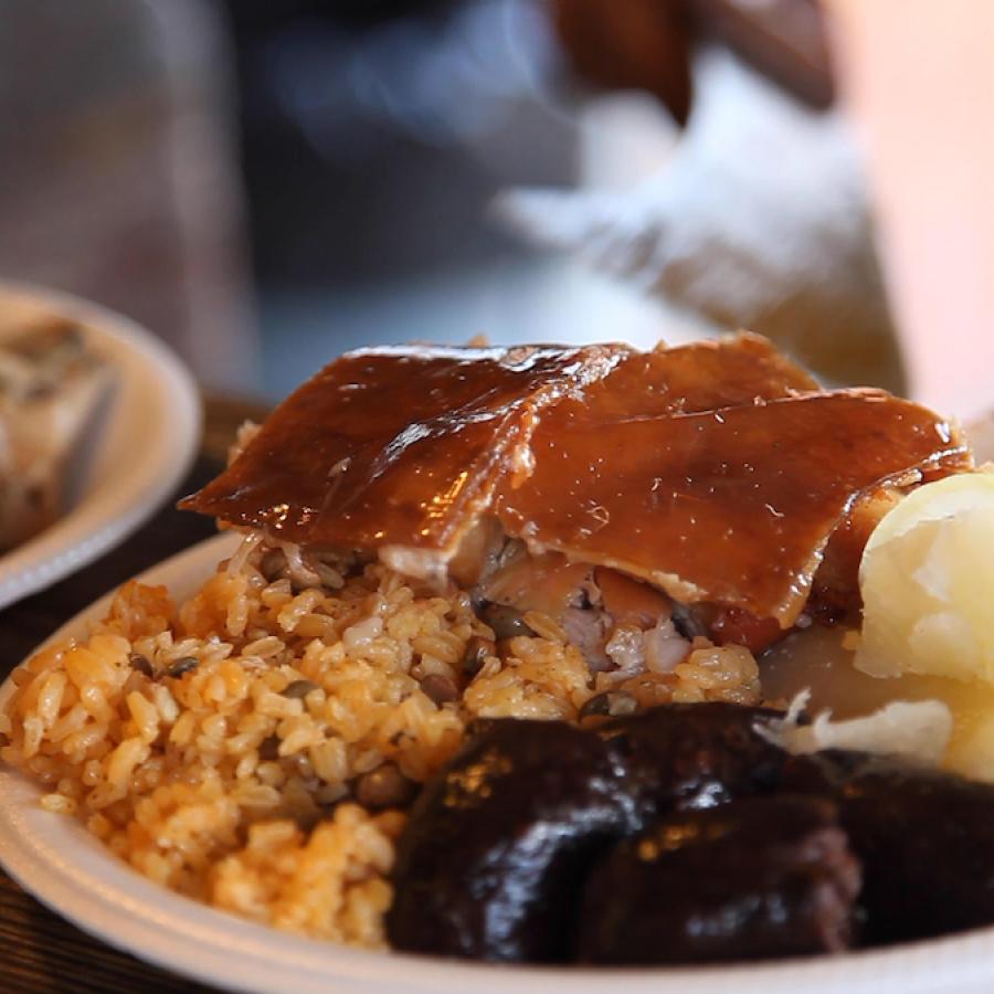 Lechón asado, arroz y gandules y morcilla en un plato.