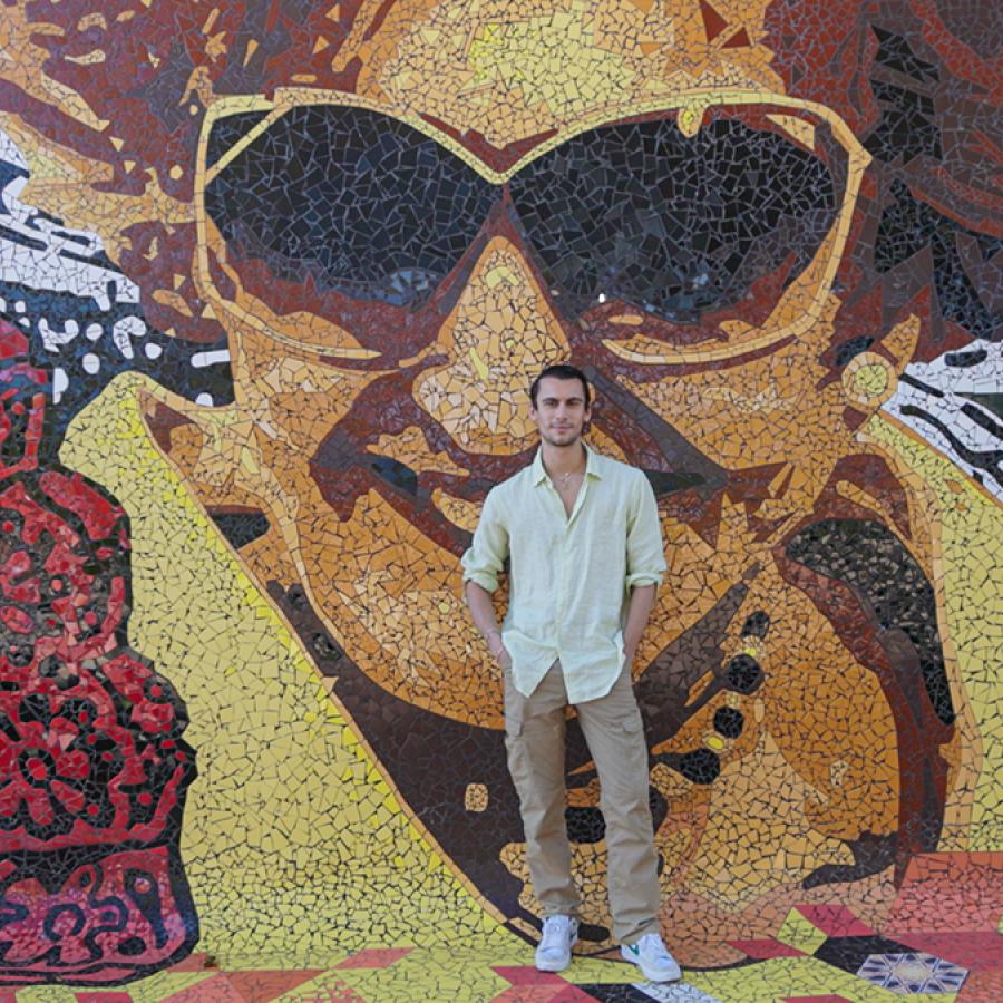 Christian Cowan poses in front of a colorful mural in Puerto Rico.