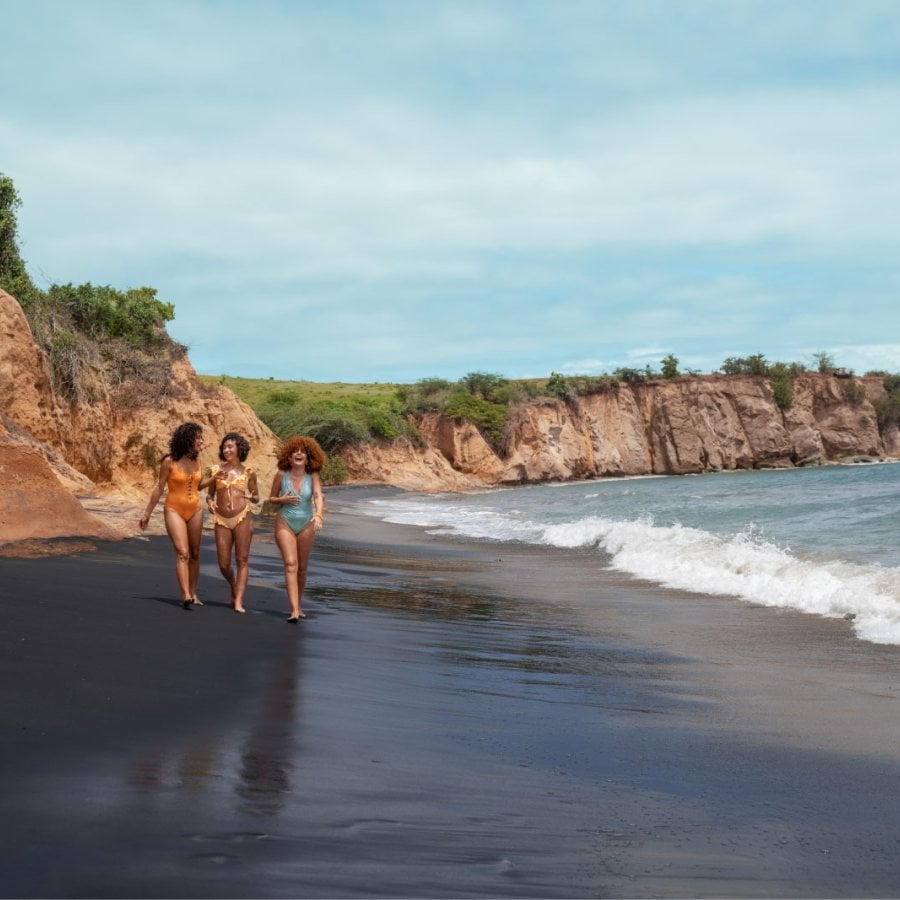 A group of women walk along Playa Negra black sand beach in Vieques, Puerto Rico