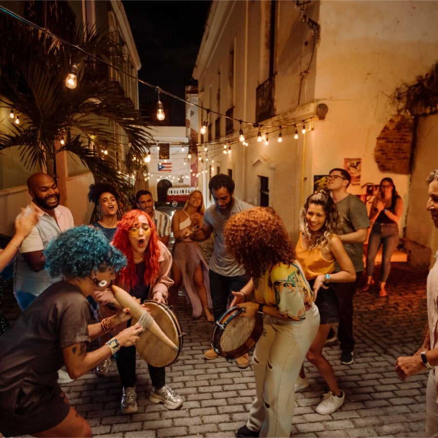 A group of people play instruments and dance in the street in Old San Juan