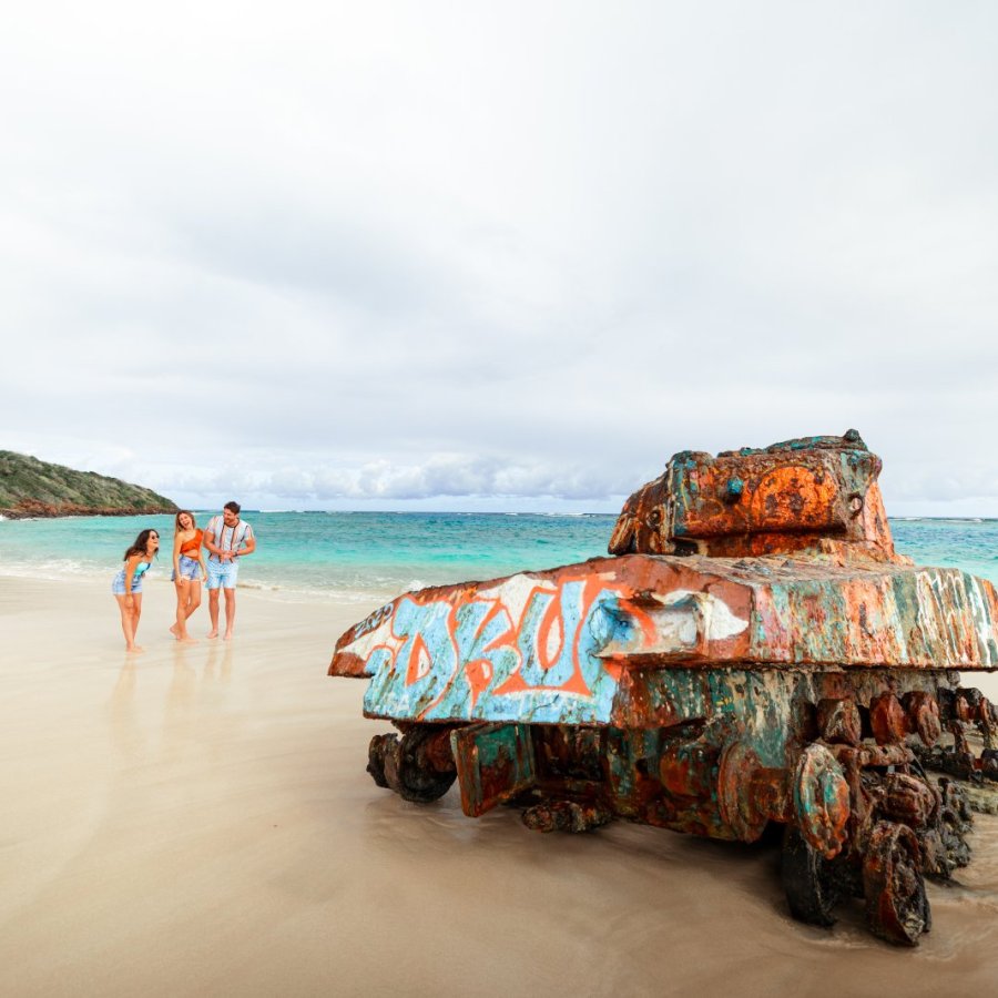 A group of friends walk toward the iconic military tank at Flamenco Beach in Culebra, Puerto Rico.