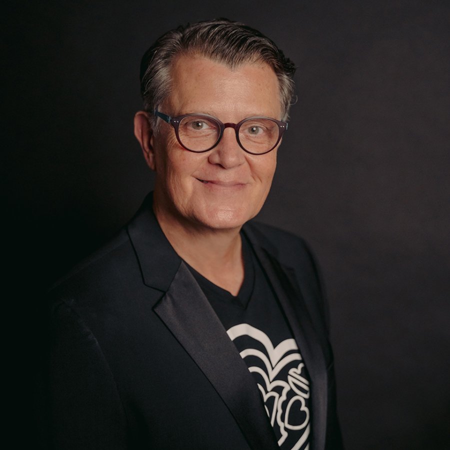 Headshot of artist Bernardo Medina, also known as BeMe, who wears eyeglasses and a black jacket.