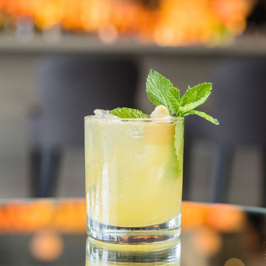 A lime-colored rum cocktail with a green garnish sits on a table.